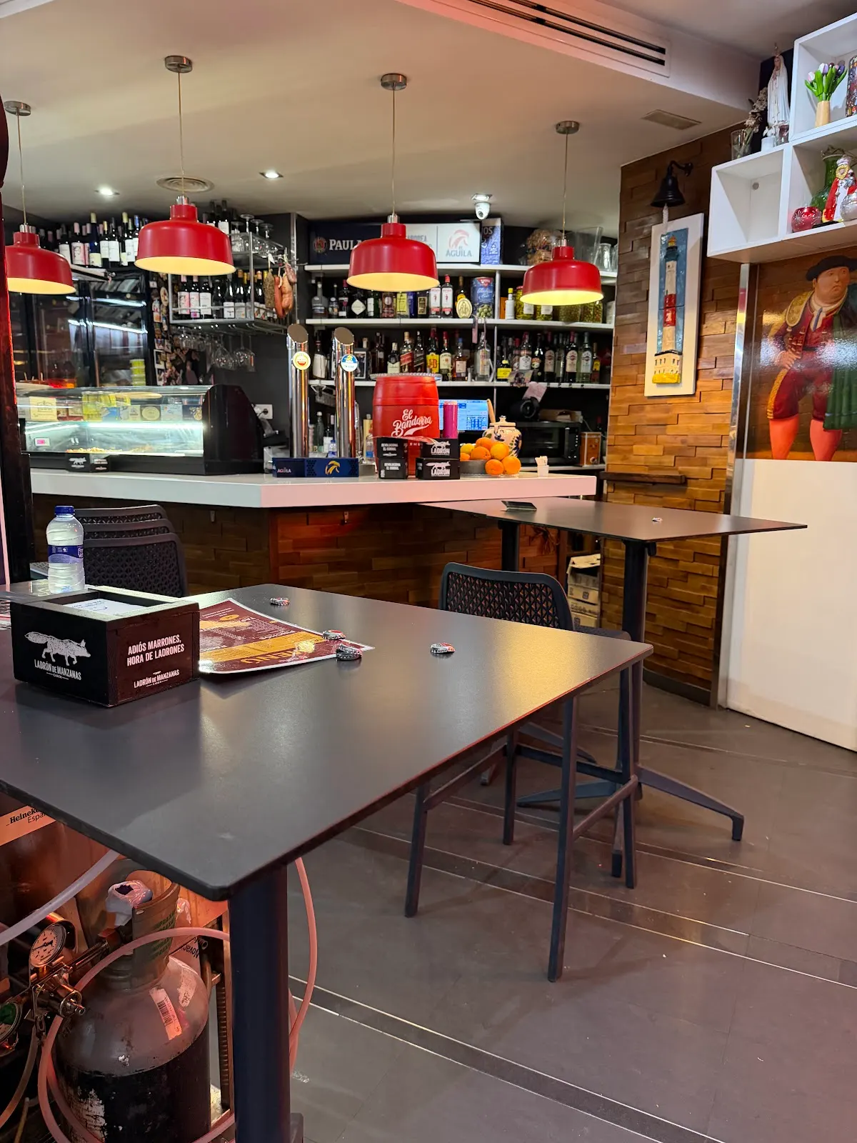 Mesas junto a la barra y lámparas rojas del interior de A’rocha